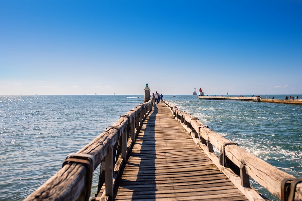 L'estacade en bois de Capbreton qui avance dans l'océan jusqu'à son phare, sous un ciel bleu