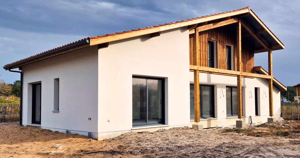 Façade de villa contemporaine à étage avec murs enduits blancs, bardage bois et toiture en tuiles.