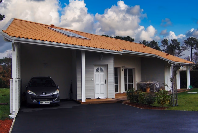 Maison individuelle de plain-pied avec abri voiture intégré, façade claire et toit en tuiles orange.