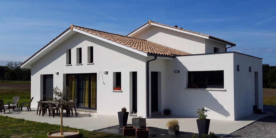 Façade de la villa moderne avec enduit blanc, toiture en tuiles et grande terrasse aménagée.