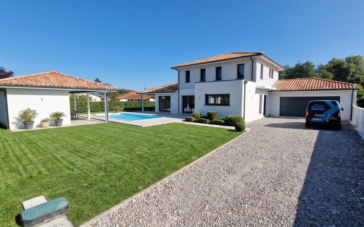 Maison individuelle contemporaine à étage avec enduit blanc, toiture en tuiles et piscine extérieure.