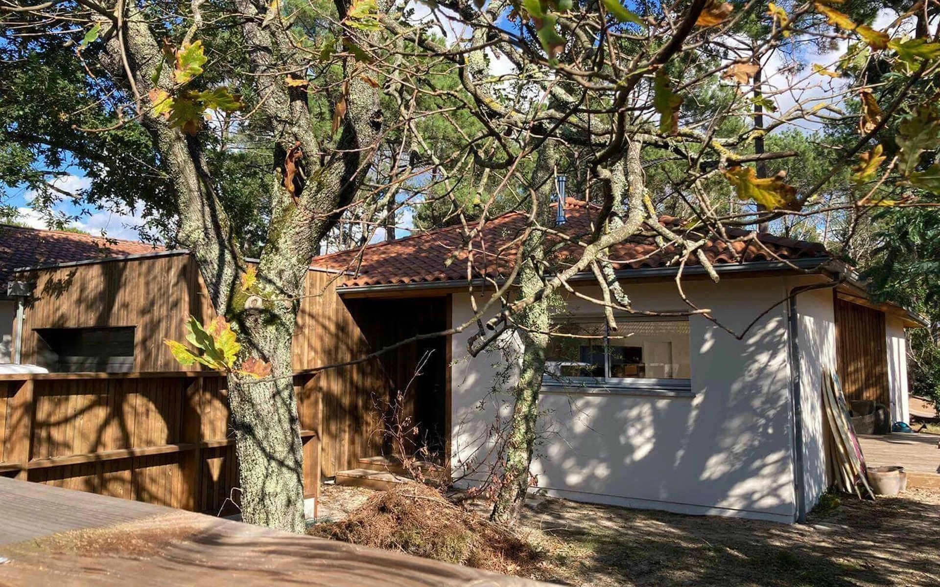 Entrée de maison en construction, toiture tuile terre cuite et bardage bois.