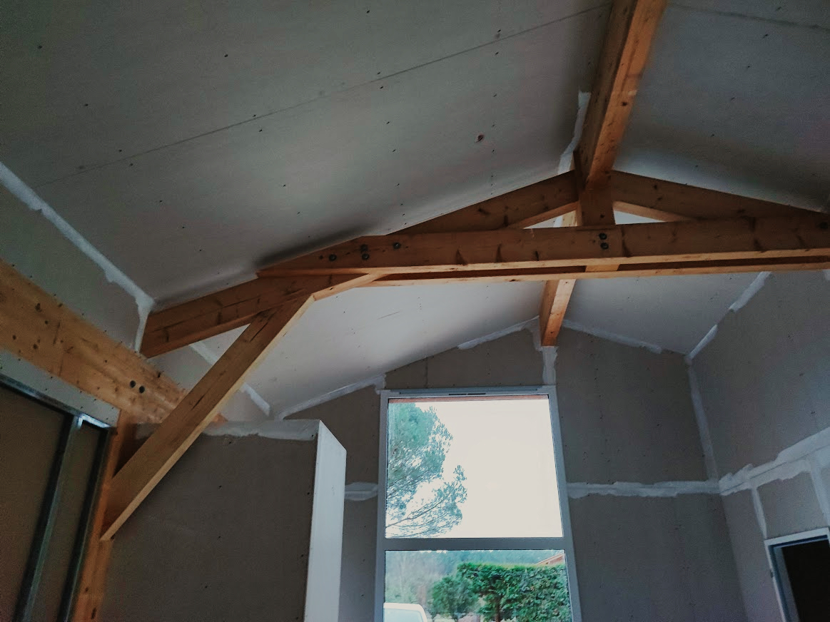 Plâtrerie maison Vielle-Saint-Girons : Les volumes se dessinent - Maison Landes Habitat Intérieur de maison à Vielle-Saint-Girons avec plâtrerie terminée et charpente apparente