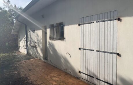 Façade d'une maison avec des volets en bois fermés et un mur blanc.