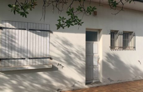 Façade d'une maison avec une porte blanche et des fenêtres à volets en bois.
