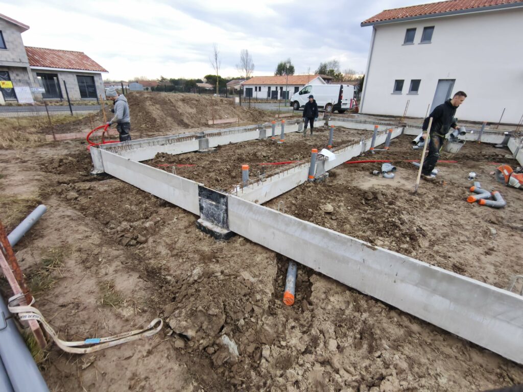 Ouvriers installant les réseaux d'évacuation dans le vide sanitaire d'une maison neuve