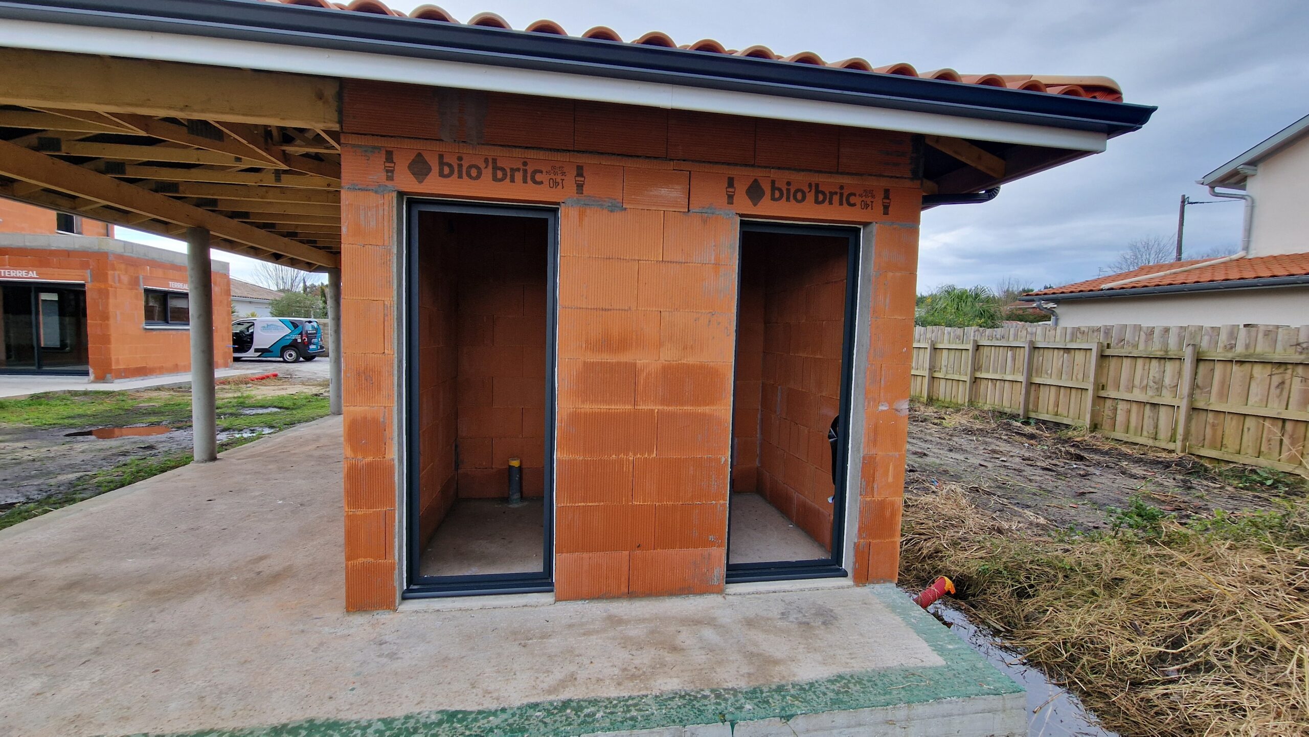 Chantier en cours : Grande Villa Familiale R+1 à Tosse (40) - Maison Landes Habitat Vue latérale du pool house d'une maison en construction à Tosse donnant sur une terrasse couverte.