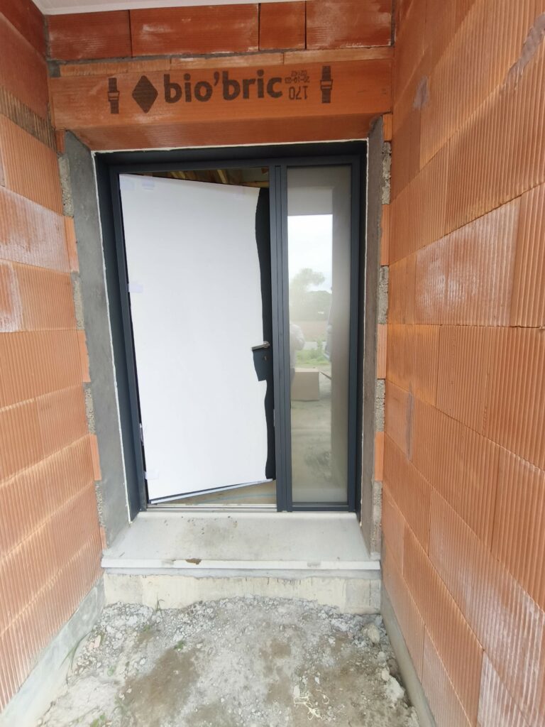 Porte d'entrée aluminium gris anthracite posée sur mur en brique Bio'bric