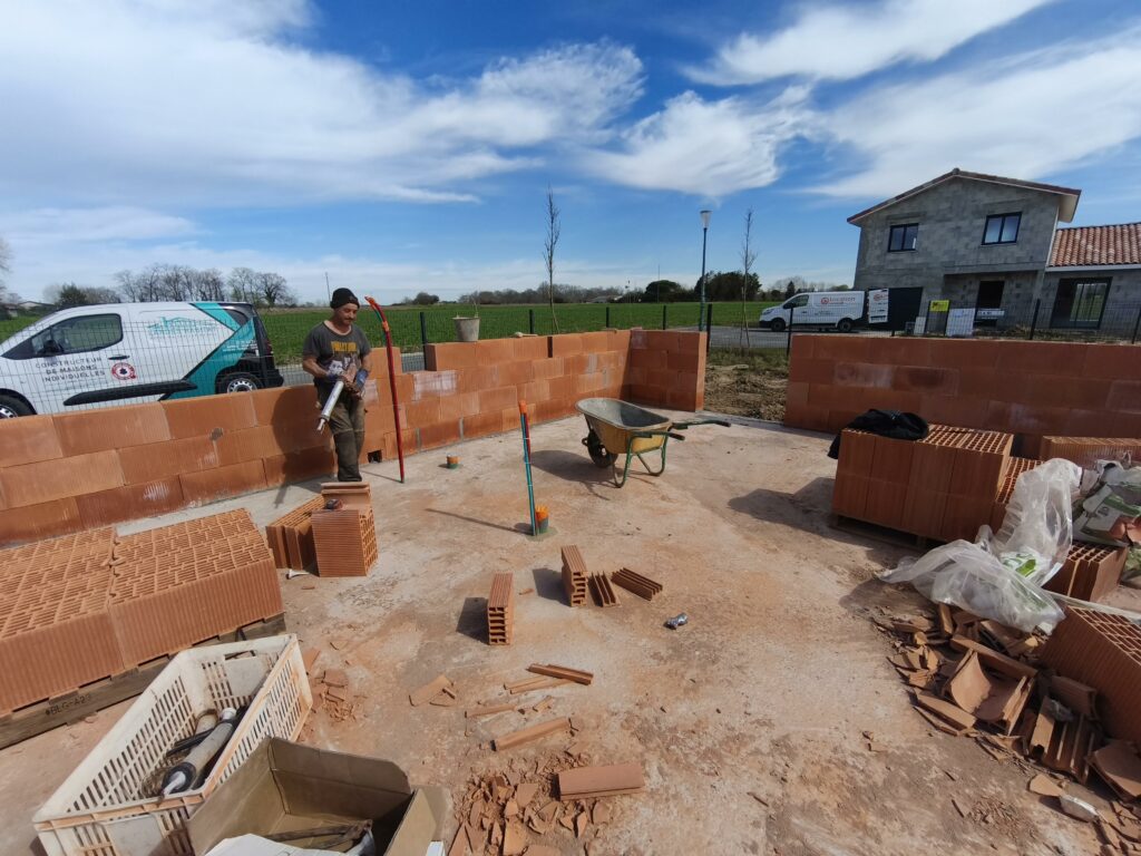 Artisan maçon posant des briques rectifiées Bio'bric sur un chantier de maison à Saubrigues