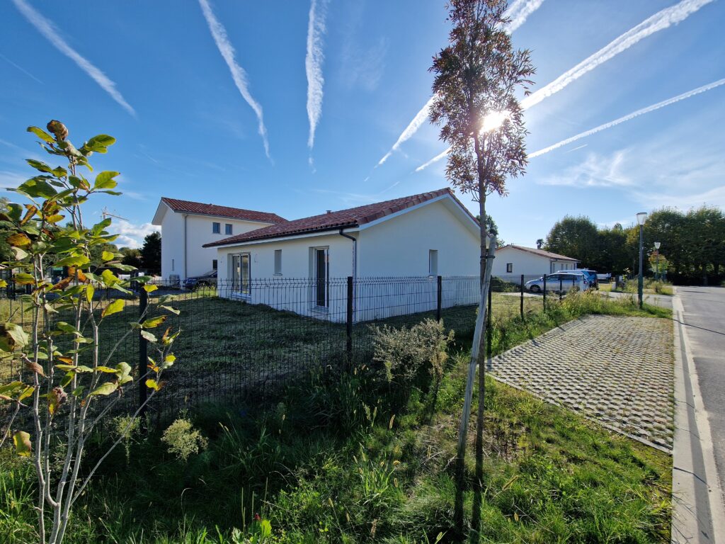 Vue ensoleillée sur le jardin et la façade latérale d'une maison livrée par Landes Habitat, secteur Maremne.