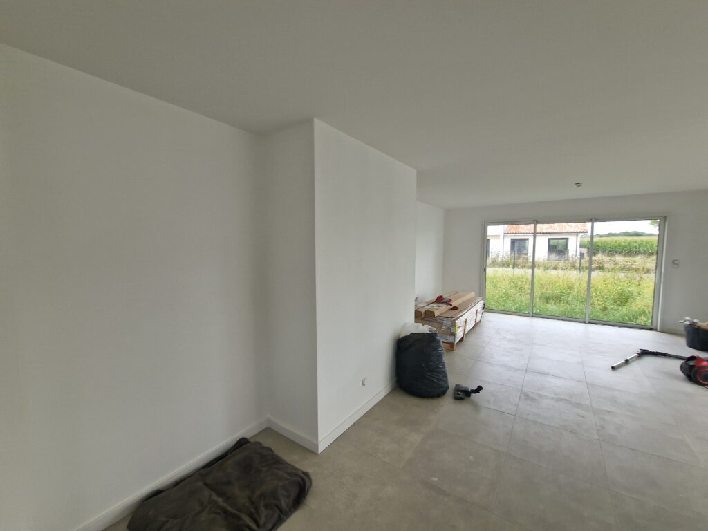 Grand salon séjour vide avec carrelage gris grand format et peinture blanche terminée