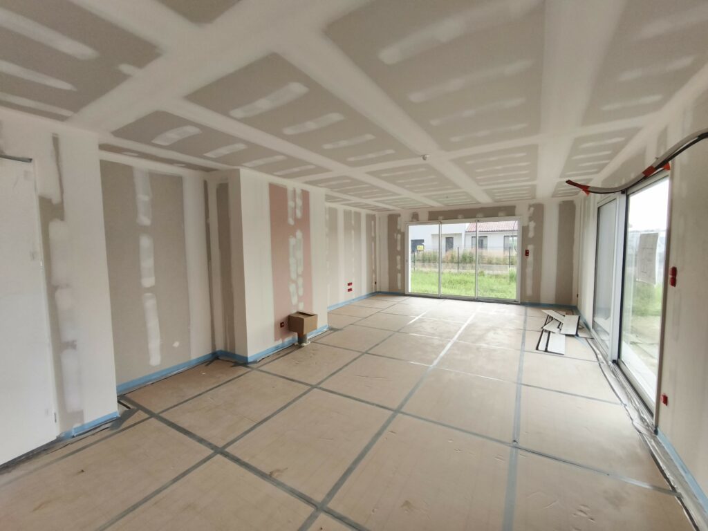 Grand salon séjour traversant avec grandes baies vitrées coulissantes dans une maison en construction à Saubrigues